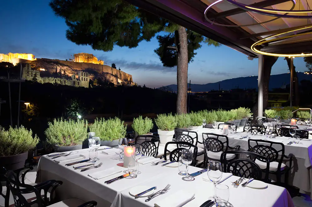 Terrace dinner set for a group with the illuminated Acropolis in the background