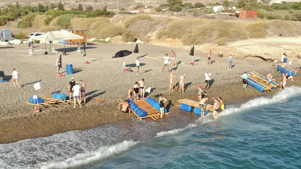 Teams building rafts on a pebble beach during a team-building activity