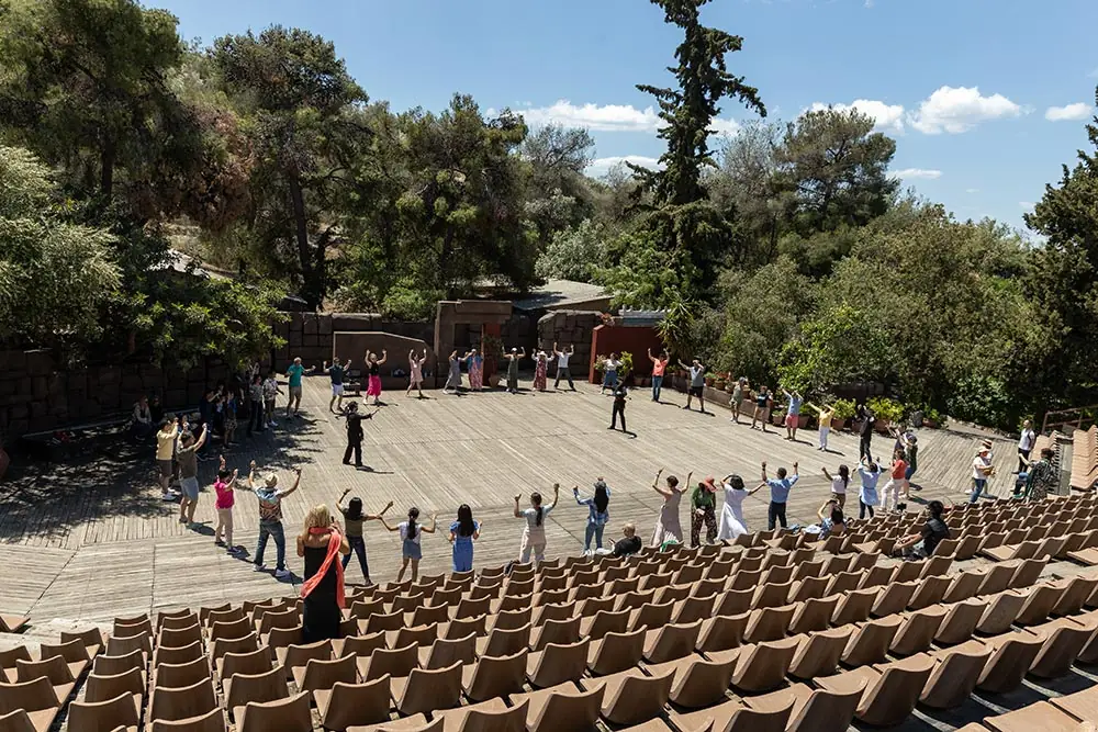 Guests learning traditional Greek dance in an open-air theatre