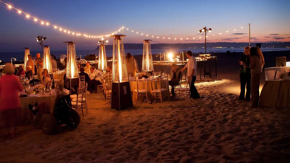 Beach dinner at dusk under string lights and patio heaters